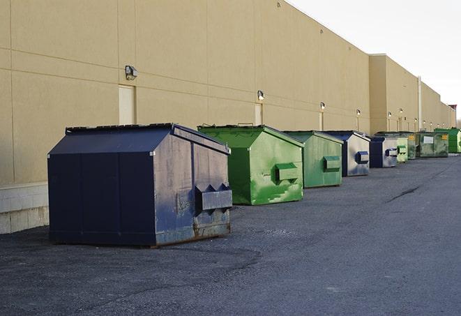 a construction worker empties a wheelbarrow of waste into the dumpster in Bannister